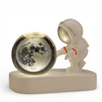 Astronaut figurine with illuminated moon crystal ball on white base, space-themed decor