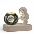 Astronaut figurine lamp with illuminated moon glass globe and cosmic design on white base