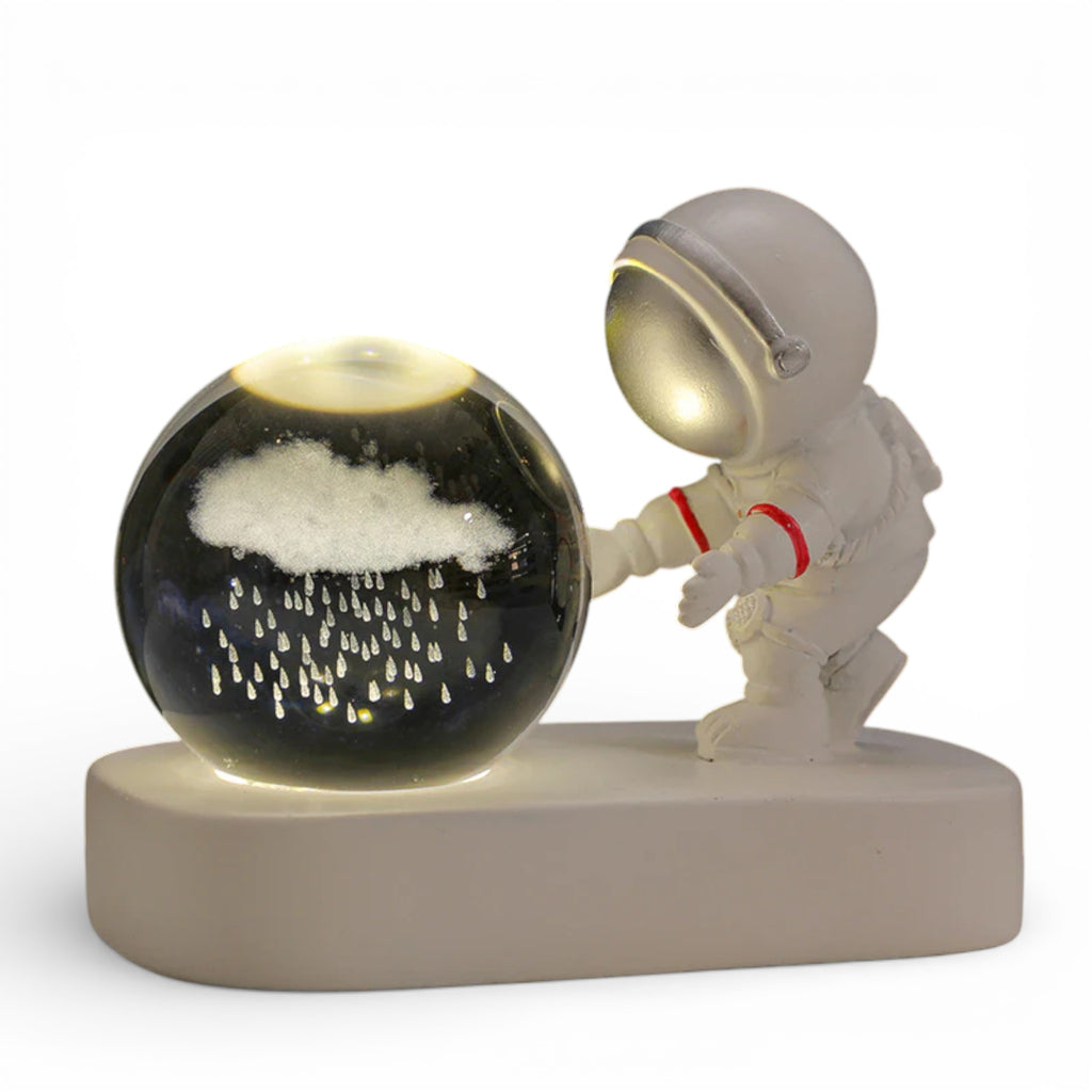 Astronaut figurine with glass globe featuring illuminated rain cloud and raindrops